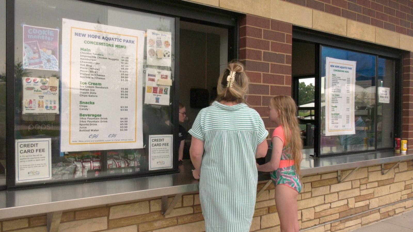 a woman and child order food at a concessions stand