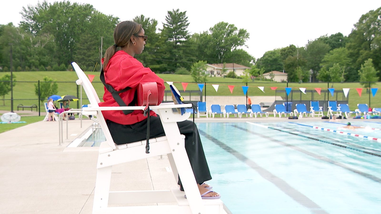 lifeguard sitting in her chair by a pool