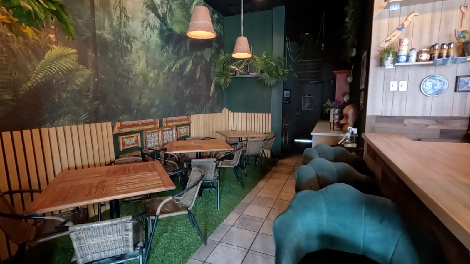 interior of a Costa Rican restaurant featuring articial grass under the tables beside the bar and wallpaper featuring tropical plants